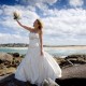 Copyright Tim Hensel photographer in Kent bride holding up white bouquet on beach while staring at the sky