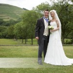 Copyright Tim Hensel photographer in Kent Bride and groom just married standing against green hills backdrop very happy