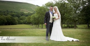 Copyright Tim Hensel photographer in Kent Bride and groom just married standing against green hills backdrop very happy