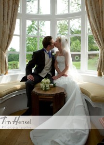 Tim Hensel photographer in Kent copyright couple sitting in bay window seat having a kiss just after ceremony aw