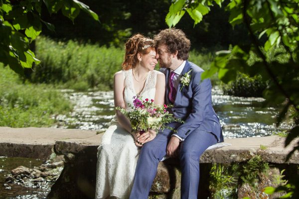 Brunette couple kissing on wall next to river mauve bouquet blue suit Wedding photographer Folkestone Tim Hensel copyright